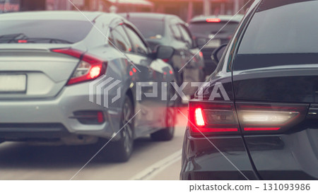 Rear side of black car with effect from brake light. Traffic jam in the city. Many cars are parked in a row on the asphalt road. 131093986