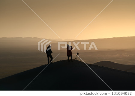 Silhouette of Two Photographers on Sand Dune in Desert during a Beautiful Sunset Silhouette of Two Photographers on Sand Dune in Desert during a Beautiful Sunset 131094052