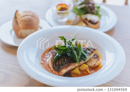 Restaurant fish and bread set, pan-fried white fish and appetizer platter, fish dish finished with tomato sauce 131094569