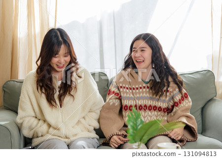 Winter friends at home, showing genuine friendship inside cozy home, two happy women enjoying relaxed conversation and warm comfort together, sharing joyful moments during cold winter season. Winter friends at home, showing genuine friendship inside cozy home, two happy women enjoying relaxed conversation and warm comfort together, sharing joyful moments during cold winter season. 131094813