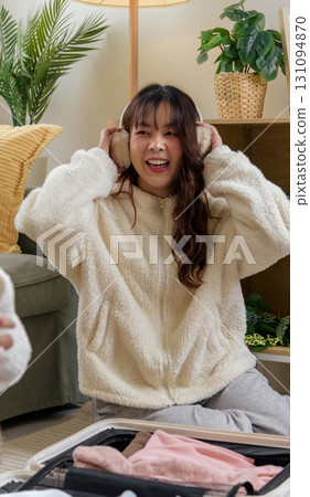 Winter day inspires warm friendship, women friends enjoy home comfort, cozy clothing earmuffs for winter journeys, happy cheerful moments at home preparing for adventure. 131094870