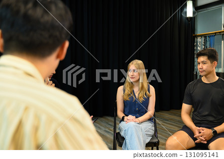 Group therapy session with diverse participants seated in a circle, listening attentively to each other 131095141