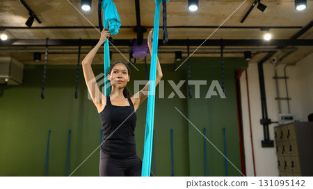 Female athlete training with aerial yoga swing, focusing on strength and balance 131095142