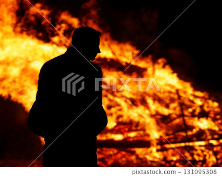 Man stands in front of a burning building 131095308