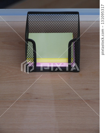 Black metal holder with yellow, green and pink paper clips 131095317