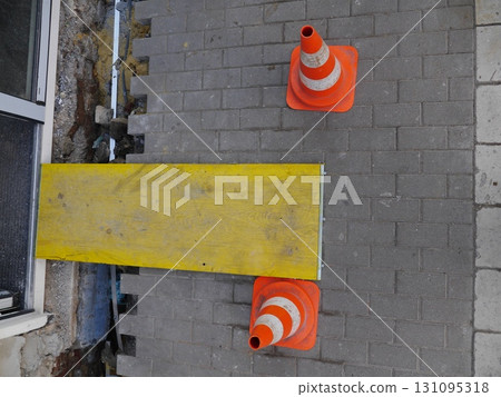 Yellow and orange wooden board with two orange and white cones on it 131095318