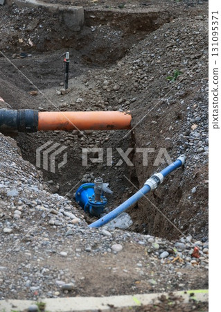 Blue pipe is laying in a hole in the ground 131095371