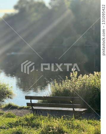 A Serene Bench Beside a Calm Lakeside, Fully Surrounded by Beautiful Natures Wonder 131095422