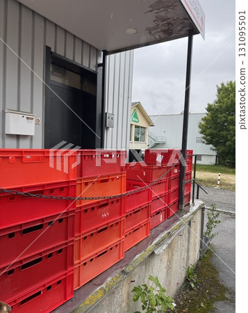 There are stacked red crates located at the entrance of a warehouse facility, ready for use There are stacked red crates located at the entrance of a warehouse facility, ready for use 131095501