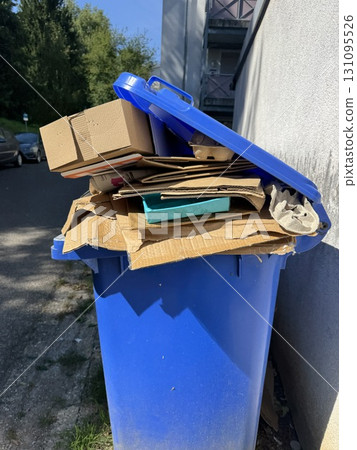 The Blue Recycling Bin is currently overflowing with cardboard waste that needs attention 131095526