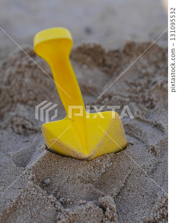 Yellow plastic shovel is sitting in the sand 131095532