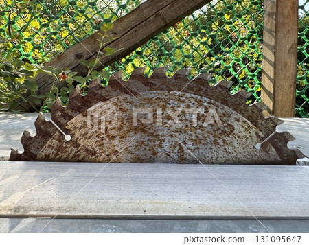 A Rusty Circular Saw Blade is resting on a Workshop Table, ready for various tasks ahead A Rusty Circular Saw Blade is resting on a Workshop Table, ready for various tasks ahead 131095647