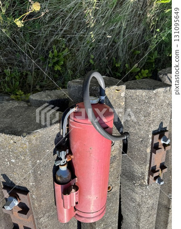 A bright red fire extinguisher stands ready on a concrete surface for potential emergencies A bright red fire extinguisher stands ready on a concrete surface for potential emergencies 131095649