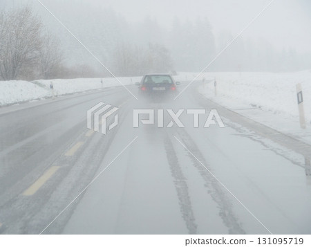 Car is driving down a snowy road with a lot of snow on the ground Car is driving down a snowy road with a lot of snow on the ground 131095719