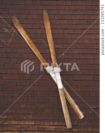 Two old wooden skis leaning against a brick wall 131095743
