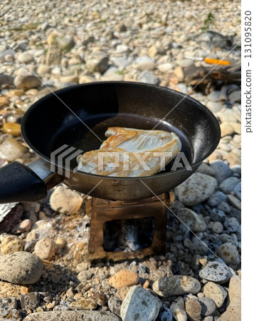 Pan of food is cooking on a rock 131095820