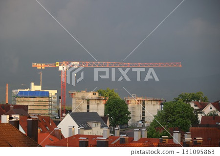Crane is seen in the distance over a city with a cloudy sky Crane is seen in the distance over a city with a cloudy sky 131095863