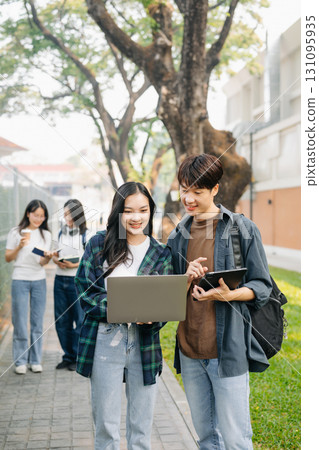 Young Asian college students and a female student group work at the campus park 131095935