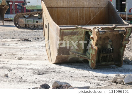 A large green bucket is sitting on the ground in front of a building A large green bucket is sitting on the ground in front of a building 131096101