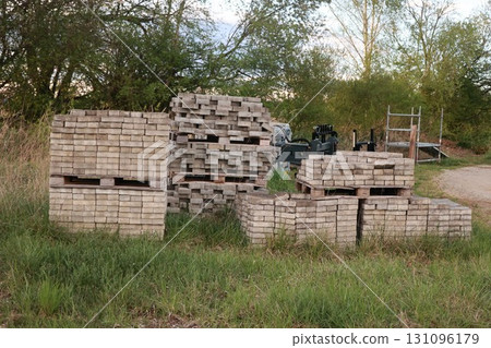 Pile of bricks and wood are stacked in a field 131096179