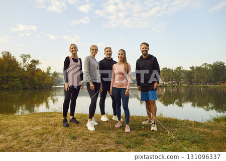 Happy young sport group of people jumping standing in a circle with hands up in nature. 131096337
