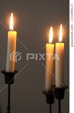 Three candles are lit and placed in a row 131096515
