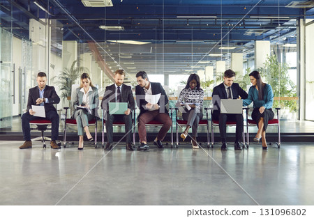 Group of diverse smart people in modern office lobby chair row sitting, working with laptops 131096802