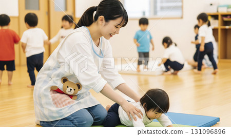 A scene of nursery teachers and children playing exercises on a gym mat 131096896