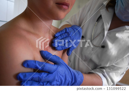 The physician is inspecting the boy's skin for health issues. The physician is inspecting the boy's skin for health issues. 131099522