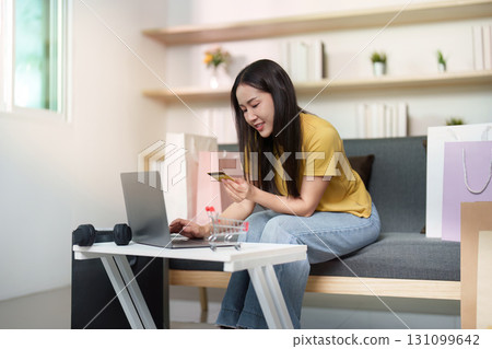 Remote Work. Young woman shopping online with laptop and credit card at home. Remote Work. Young woman shopping online with laptop and credit card at home. 131099642