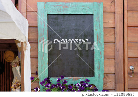 Dealing, merger and acquisition, business cooperation concept. Copy space. ENGAGEMENT written on Charming wooden wall with a turquoise-framed chalkboard 131099685