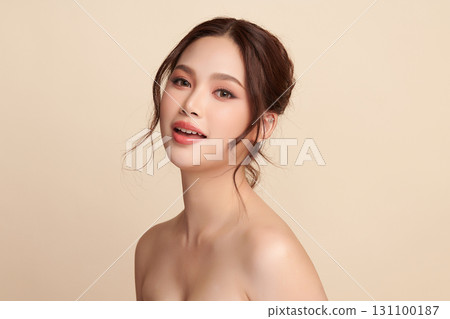 A beautiful young Asian woman with clean, fresh skin against a beige background. Skincare, facial treatment, cosmetology, beauty, and spa. An elegant portrait of an Asian woman. 131100187