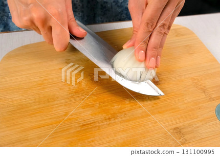 Chef woman hands skillfully chopping white onion on cutting board on kitchen. 131100995