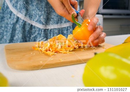 Woman hands cutting removing seeds from orange bell pepper cooking on kitchen. 131101027