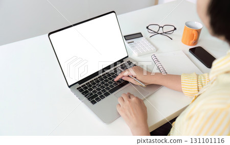 Work from Home: Individual typing on laptop while taking notes in a cozy workspace 131101116