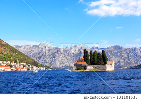 Picturesque view of embankment with old houses, Adriatic sea and St. George Island, Perast, Montenegro. Beautiful seascape with Saint George monastery. Topic of summer vacation, travel, cruises, tours 131101535