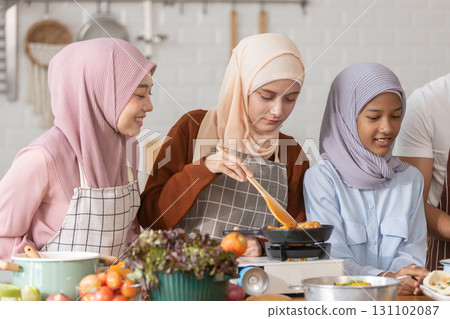 Muslim family cooking together in modern kitchen. Woman in hijab stirring food, child watching, and man preparing ingredients. Concept of halal food, family bonding, healthy lifestyle, and home Muslim family cooking together in modern kitchen. Woman in hijab stirring food, child watching, and man preparing ingredients. Concept of halal food, family bonding, healthy lifestyle, and home 131102087