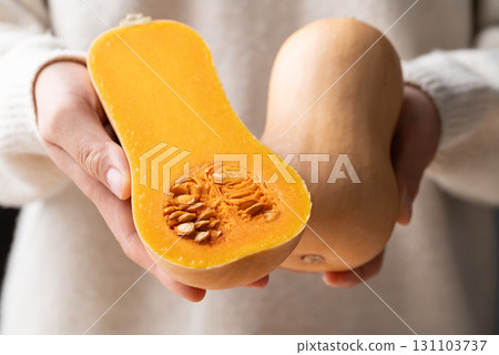 Half butternut squash pumpkin holding by woman hand Half butternut squash pumpkin holding by woman hand 131103737