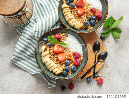 Healthy breakfast bowls with yogurt, granola, banana, and berries 131103995