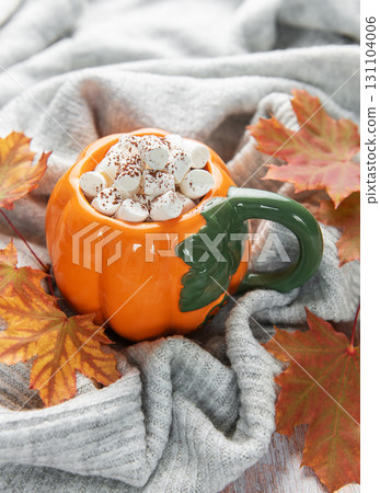 Pumpkin mug of hot chocolate with marshmallows and autumn leaves Pumpkin mug of hot chocolate with marshmallows and autumn leaves 131104006
