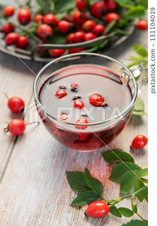 Steaming rosehip tea with fresh rose hips on rustic wooden table Steaming rosehip tea with fresh rose hips on rustic wooden table 131104019