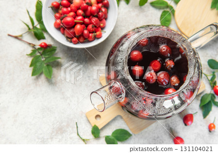 Steaming rosehip tea brewing in glass teapot with fresh rose hips Steaming rosehip tea brewing in glass teapot with fresh rose hips 131104021