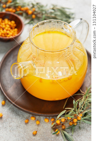 Sea buckthorn hot drink in glass teapot on wooden tray 131104027
