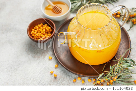 Sea buckthorn hot drink in glass teapot on wooden tray 131104028