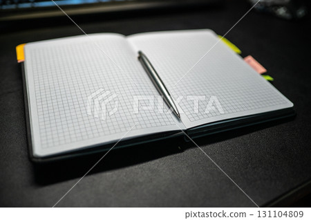 An Open Notebook accompanied by a Pen set on a Dark Desk inviting creativity and productivity 131104809