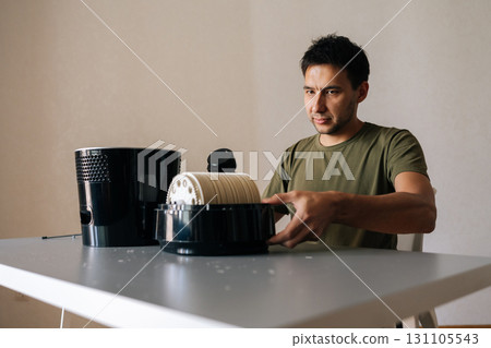 Portrait of focused technician cleaning air humidifier filter with vacuum cleaner, performing maintenance to ensure optimal air quality and promote healthy environment in home setting. 131105543