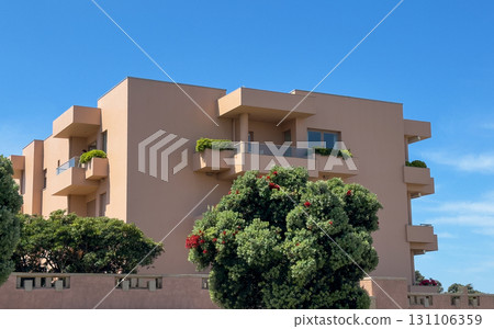 Apartment building exterior. Modern urban structure with peach facade, balconies, geometric design, 131106359