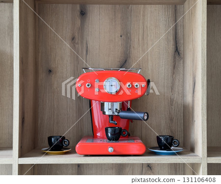 Coffee machine in kitchen interior. Red retro appliance on wooden shelf, cozy modern style with cups Coffee machine in kitchen interior. Red retro appliance on wooden shelf, cozy modern style with cups 131106408