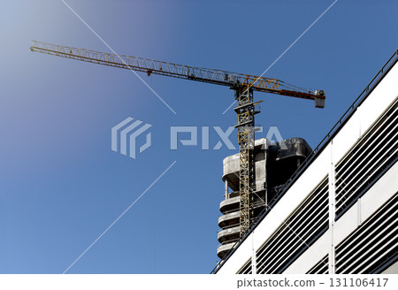 Construction site in sunlight. Skyscraper tower with crane, modern facade, exterior structure, 131106417