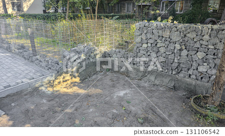 Stone fence construction. Mesh base with stones inside. Open space design 131106542